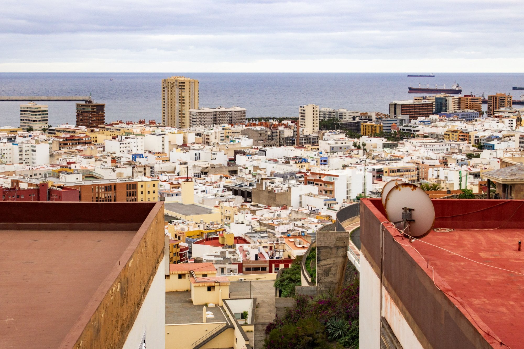 Vista aérea de una ciudad costera con azoteas, edificios blancos y barcos en el mar
